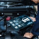 Ako zistiť, akú poruchu má vaše vozidlo? Mechanik diagnostikuje poruchu vozidla pomocou digitálneho rozhrania nad otvoreným motorovým priestorom auta.
