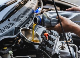 Automechanik nalieva motorový olej do motora pri bežnej údržbe v autoservise.