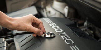 Automechanik kontroluje hladinu motorového oleja pomocou mierky pri otvorenej kapote vozidla.